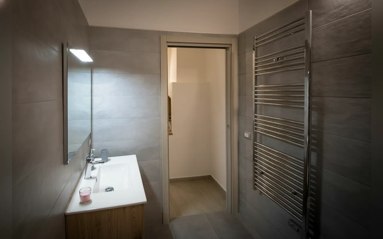 Il bagno con specchio, lavabo e termoarredo