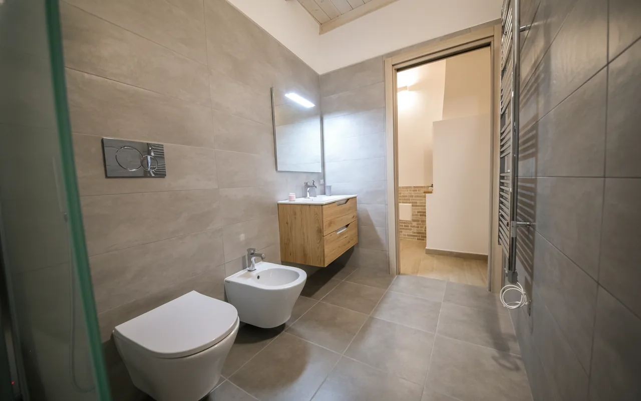 Bagno con doccia, lavabo sospeso e termoarredo
